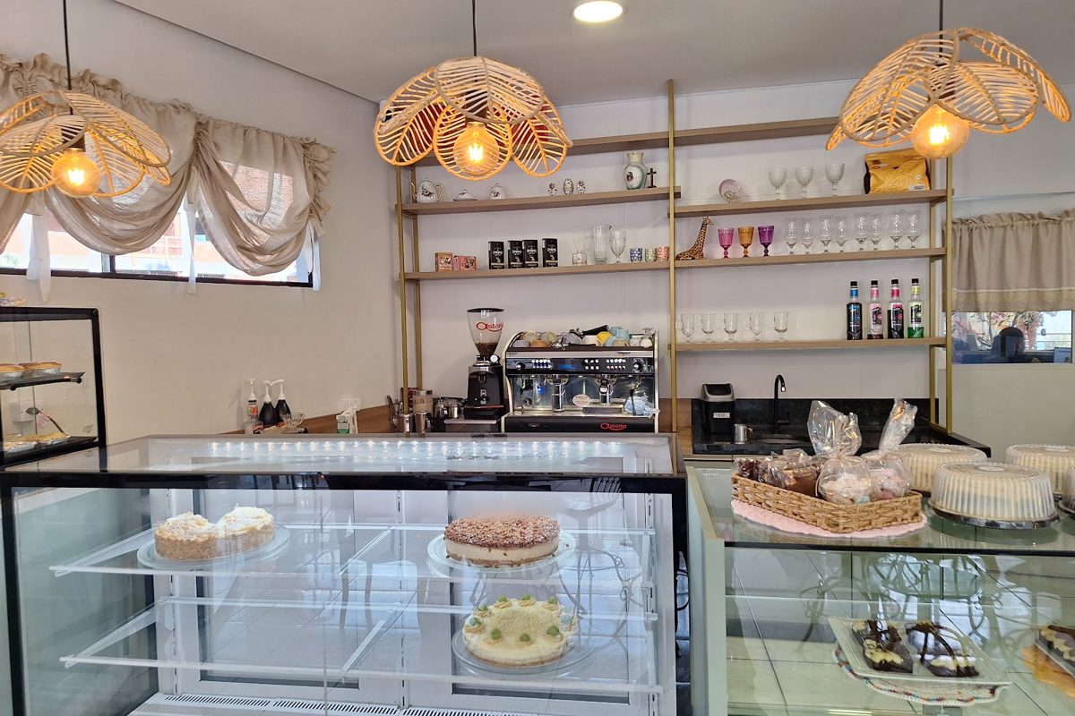 Balcão do café com prateleiras douradas, máquina de espresso e luminárias de palha